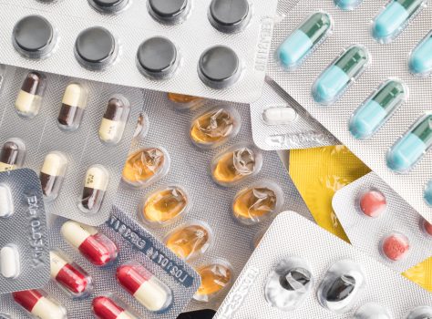 packings of pills and capsules of medicines on white background